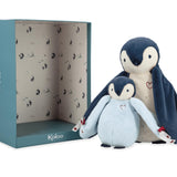 Two plush penguins in front of a Kaloo branded box on a white background
