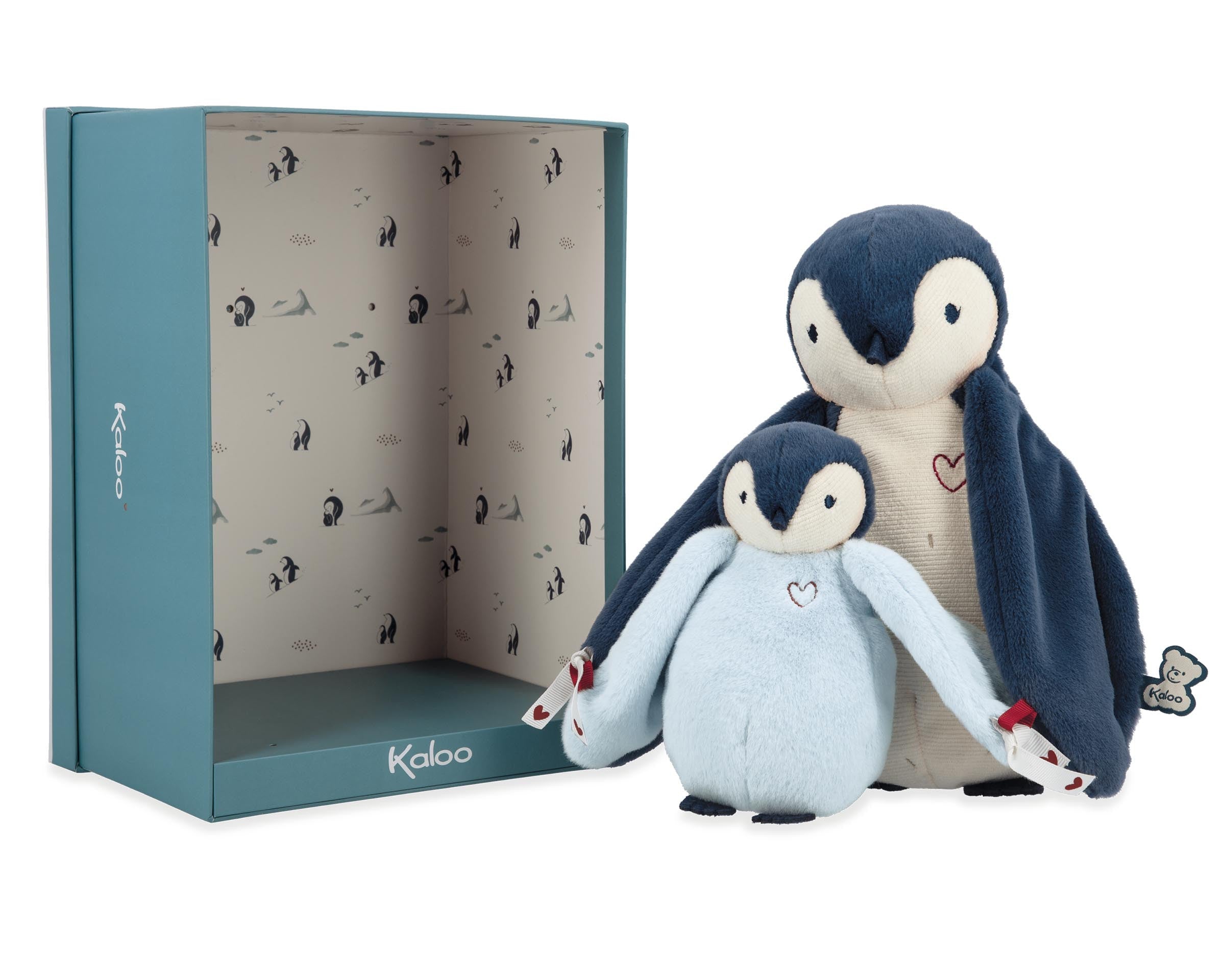 Two plush penguins in front of a Kaloo branded box on a white background
