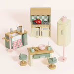 Set of wooden toy kitchen furniture on a light pink background
